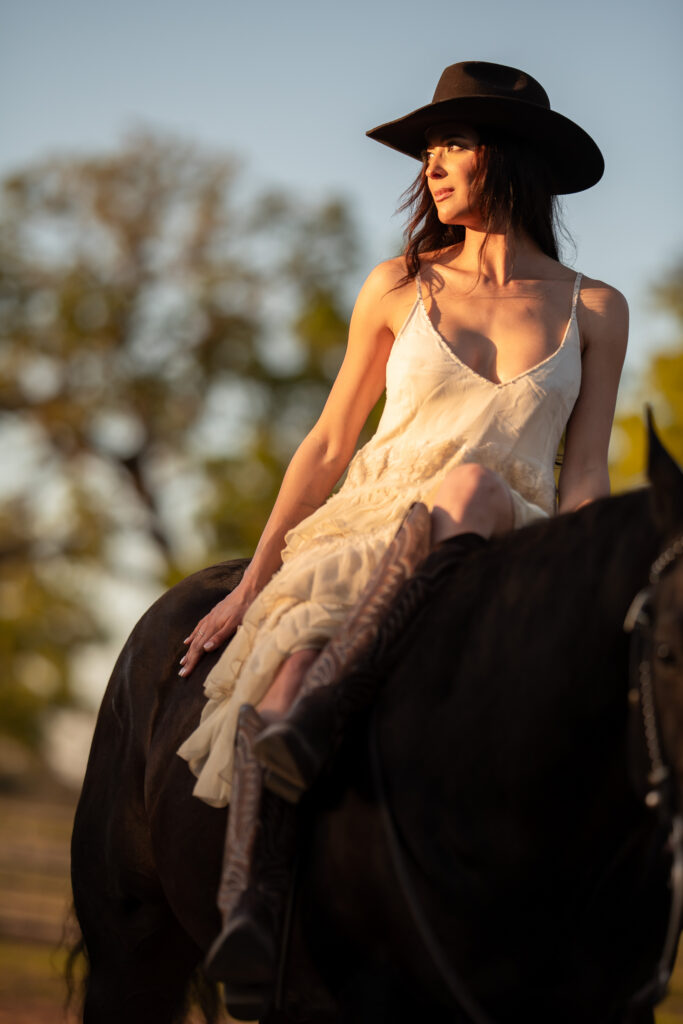 woman sitting on her horse staring towards the sun