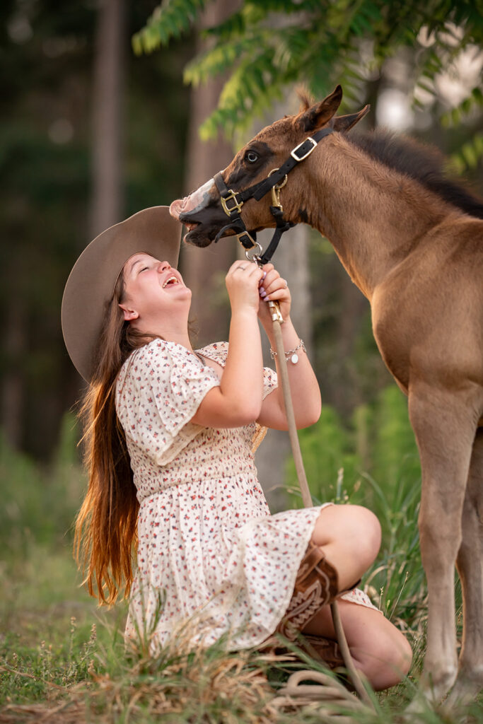 a little girl laughing while her foal makes a funny face